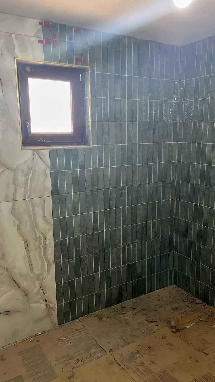 Pared de baño con azulejo verde y revestimiento veteado