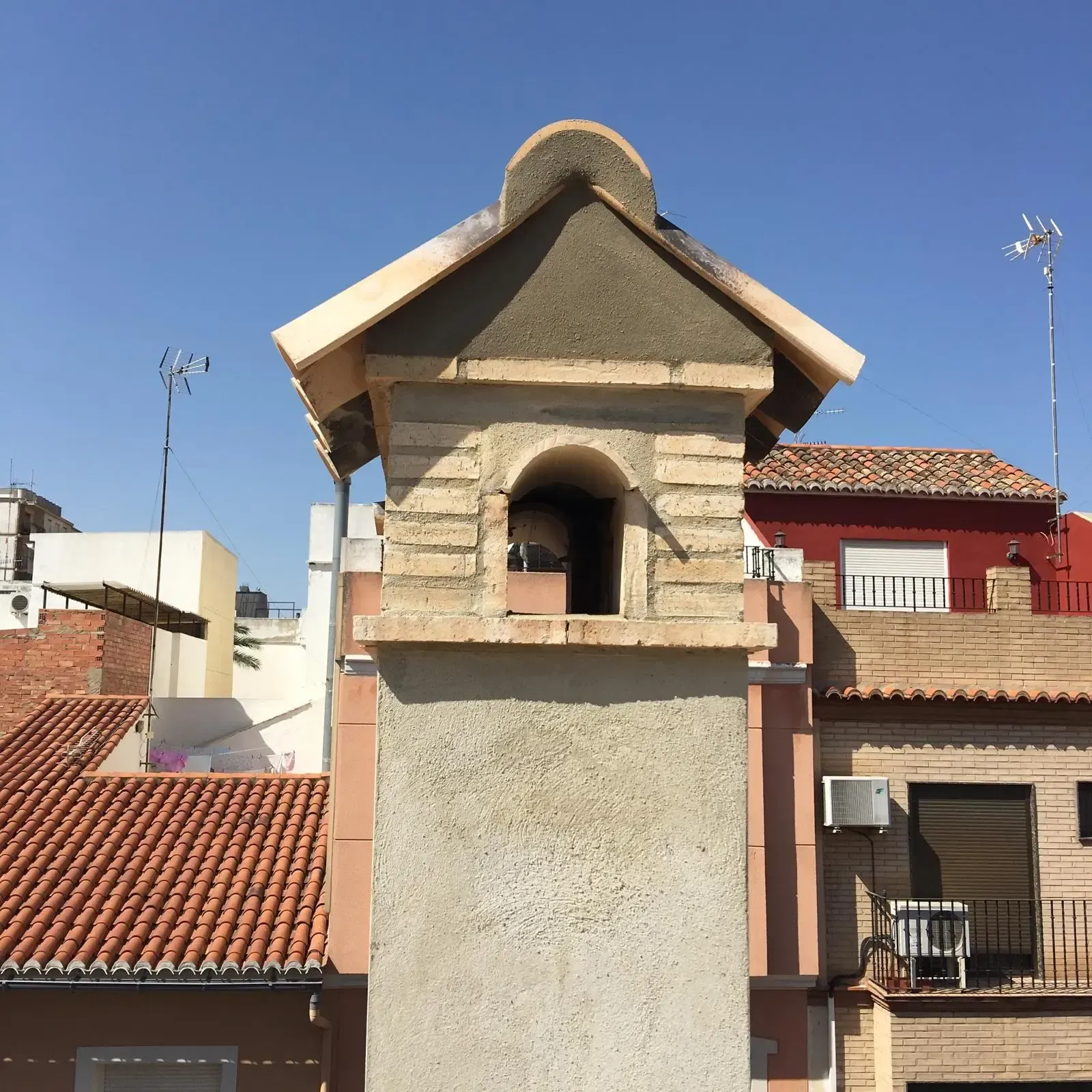 Chimenea de ladrillo con remate de tejas sobre una cubierta