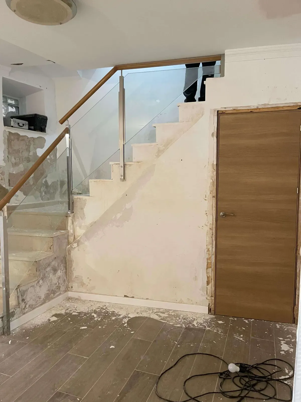 Escalera con paredes dañadas por la humedad y barandilla de madera con paneles de cristal