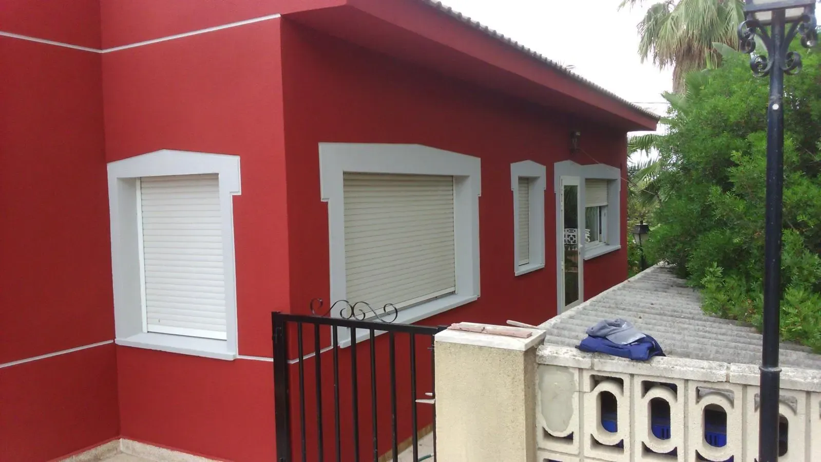 Fachada de vivienda pintada en rojo con molduras blancas en las ventanas, trabajo de GLDECOR & BUILDING
