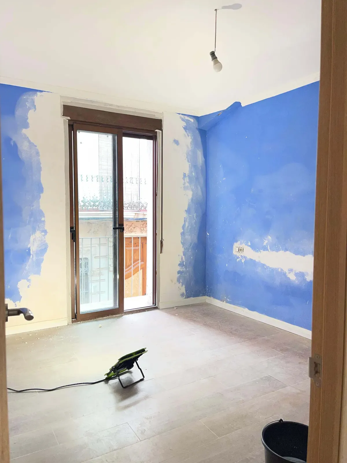 Habitación con una pared en proceso de saneado y pintura